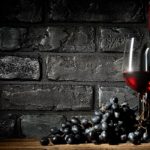 Bunch of grapes and wine on a black brick background.When: 04 Feb 2016