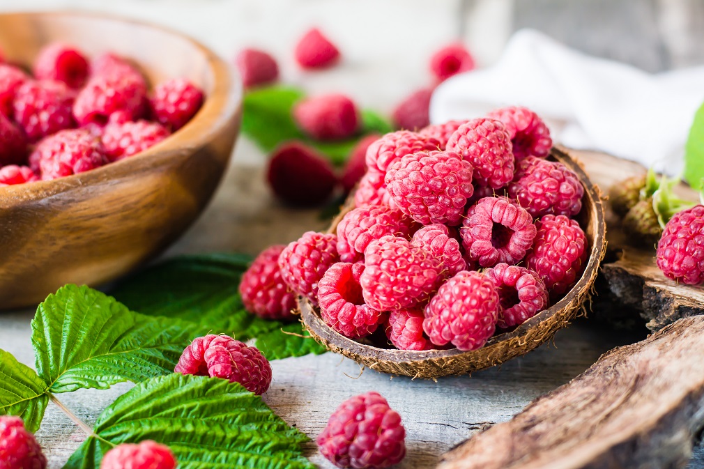 Raspberry in a bowl and in a plate, berries and leaves on a shab