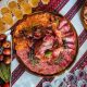 Slices of smoked meat served with greenery lie on the wooden tra